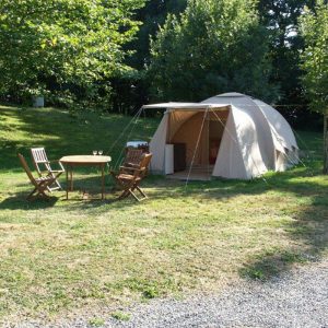 Een beige tent en een tafel met stoelen op de natuurcamping